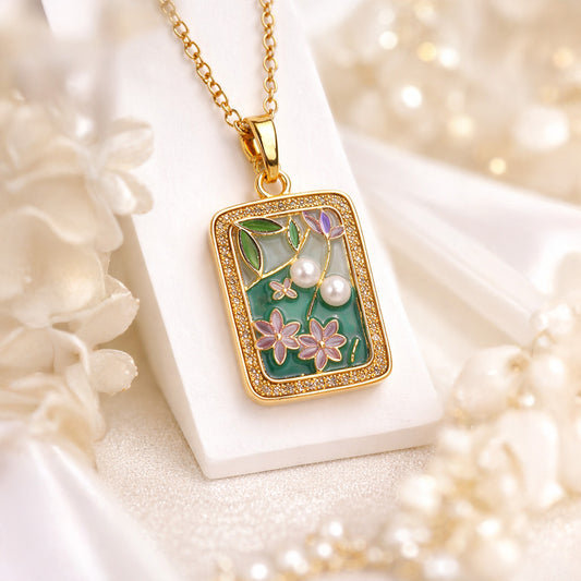 Gold necklace with a decorative pendant featuring floral designs and pearls on a soft white background.