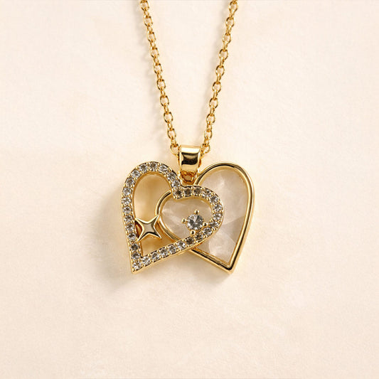 Gold heart-shaped necklace with embedded stones on a beige background