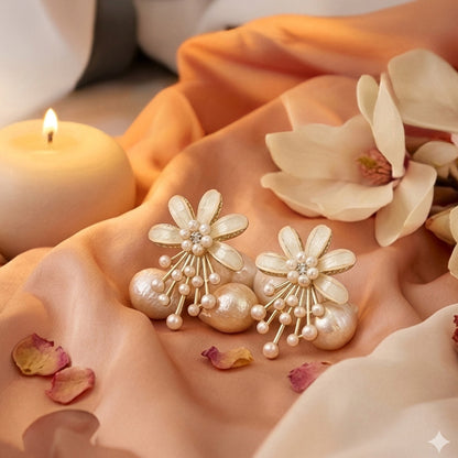 Floral earrings with pearls on a soft fabric background with flowers and a candle.