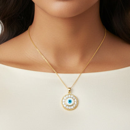 Gold necklace with a round pendant featuring a blue eye design on a plain background