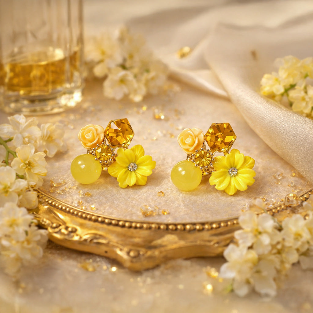 Yellow floral earrings on a decorative plate with flowers and a glass of wine in the background