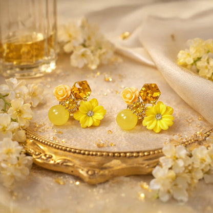 Yellow floral earrings on a decorative plate with flowers and a glass of wine in the background